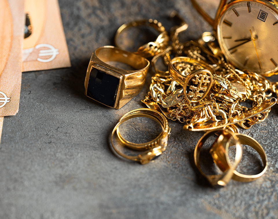 Gold jewelry and watch on gray surface.