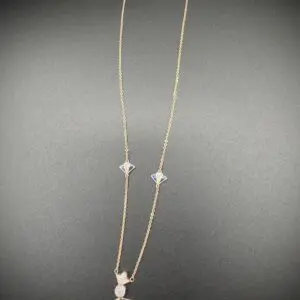 Delicate silver necklace with star and cat charms on a grey background.