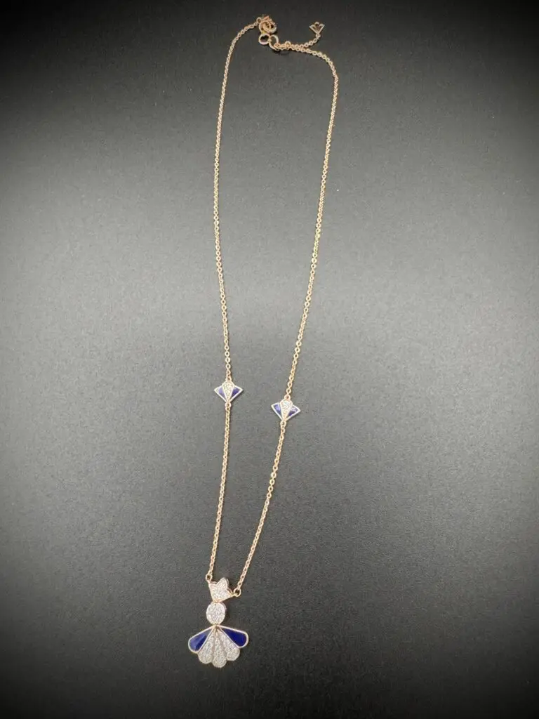 Delicate silver necklace with star and cat charms on a grey background.