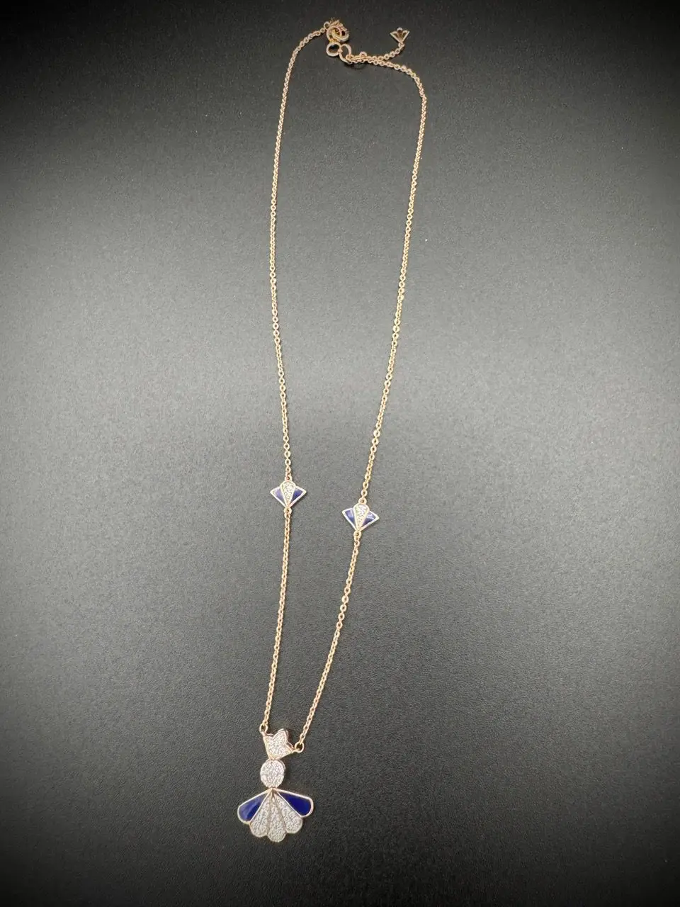 Delicate silver necklace with star and cat charms on a grey background.