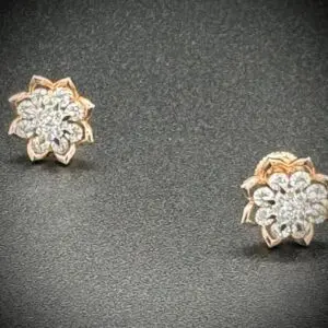 Elegant floral diamond earrings with a gold base on a dark background.