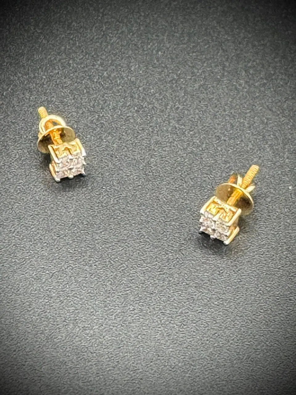 Elegant gold and diamond stud earrings on a dark surface.