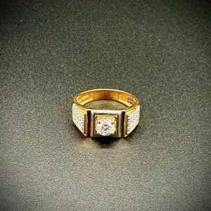Gold ring with a central diamond on a dark textured surface.