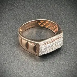 Close-up of a gold ring with diamond accents on a dark surface.