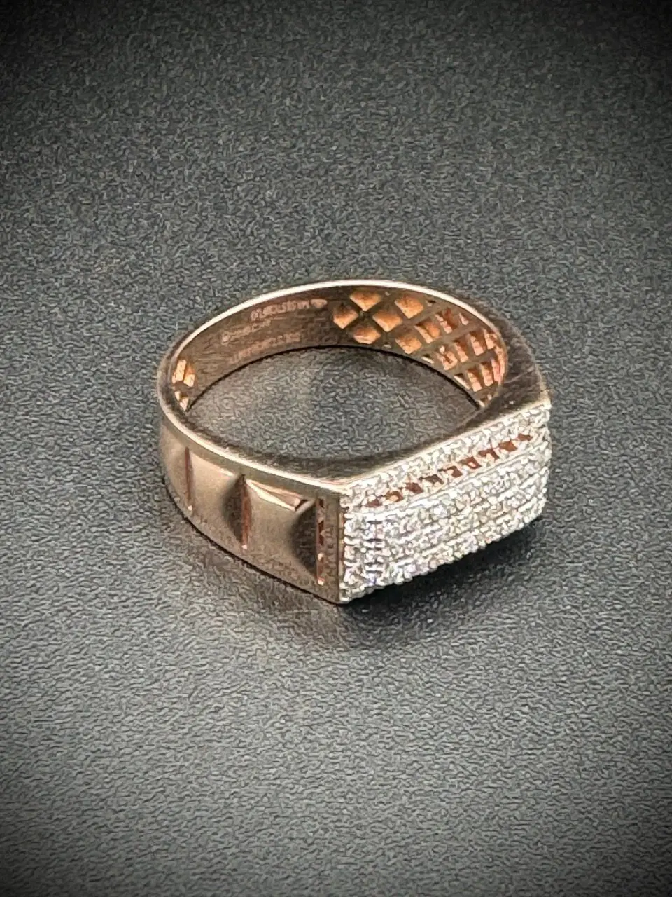Close-up of a gold ring with diamond accents on a dark surface.