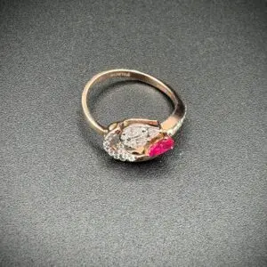 Elegant ring with a clear and a pink gemstone on a dark surface.
