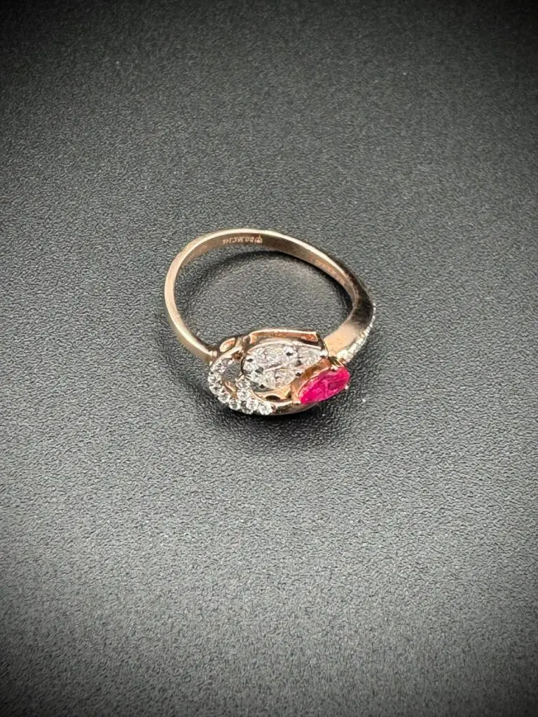 Elegant ring with a clear and a pink gemstone on a dark surface.