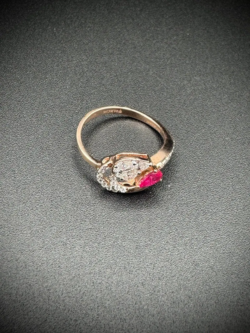 Elegant ring with a clear and a pink gemstone on a dark surface.