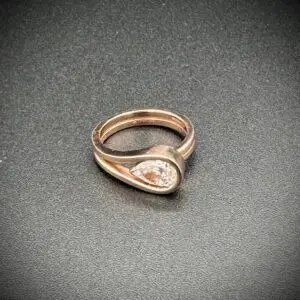 Elegant rose gold ring with a teardrop-shaped design and central gem.