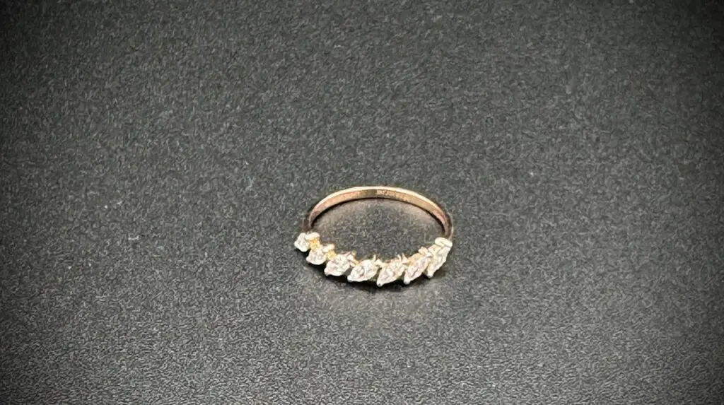 Elegant gold ring with leaf-shaped diamonds on a black surface.