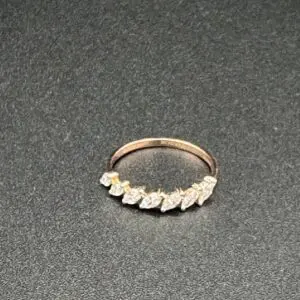 Elegant gold ring with leaf-shaped diamonds on a black surface.