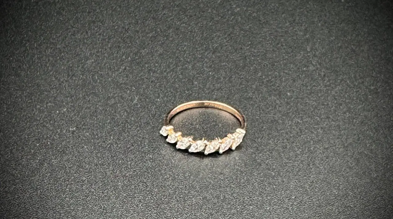 Elegant gold ring with leaf-shaped diamonds on a black surface.