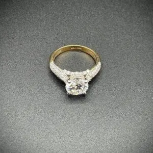 Gold diamond engagement ring on black background.