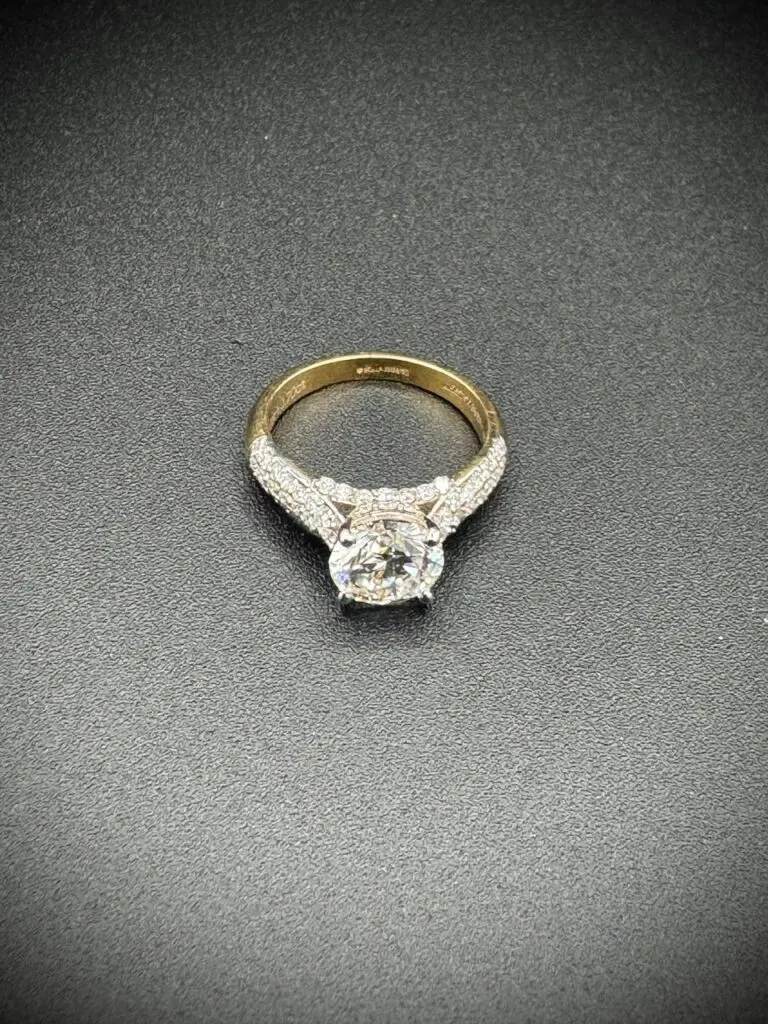 Gold diamond engagement ring on black background.