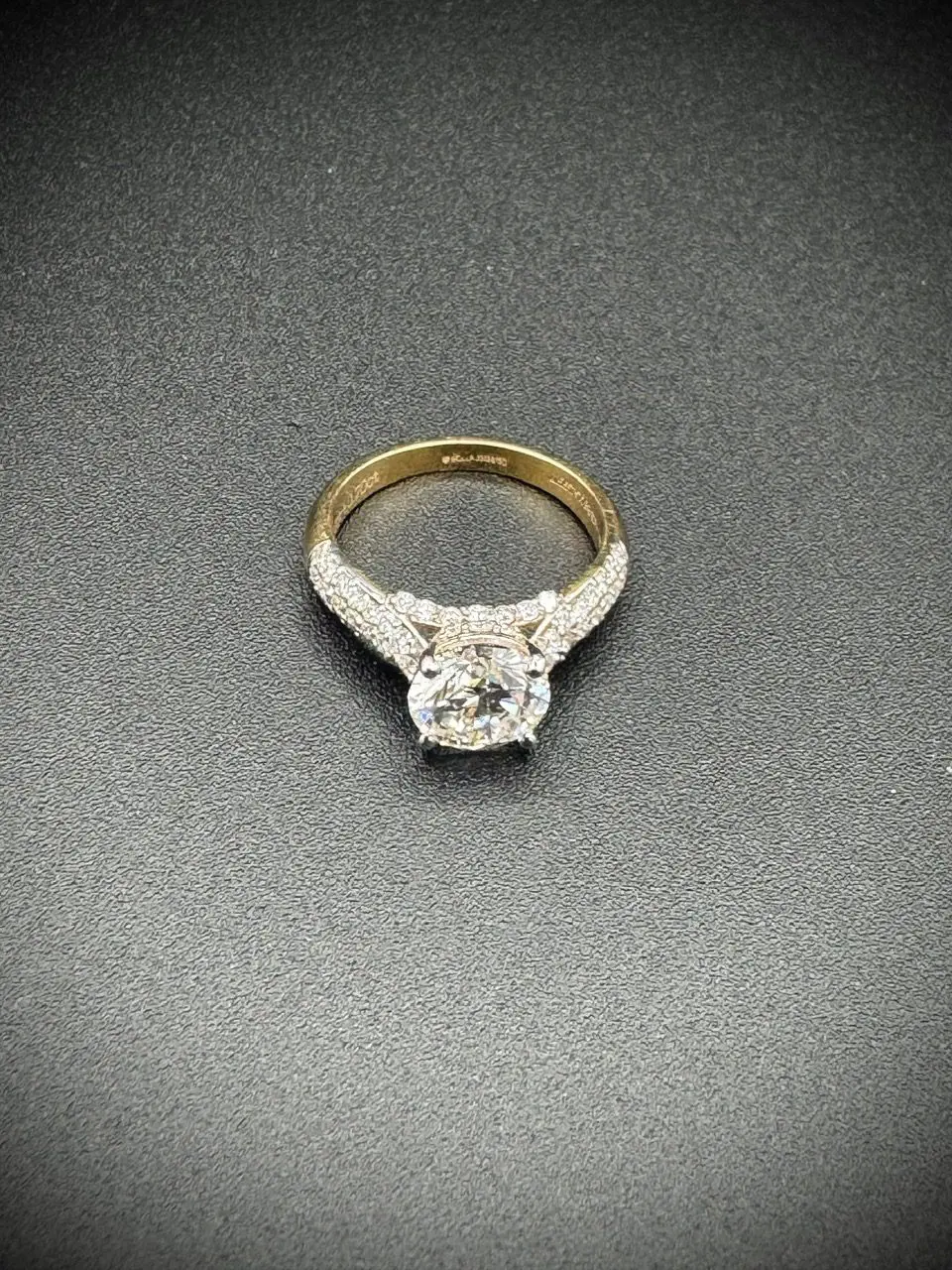 Gold diamond engagement ring on black background.