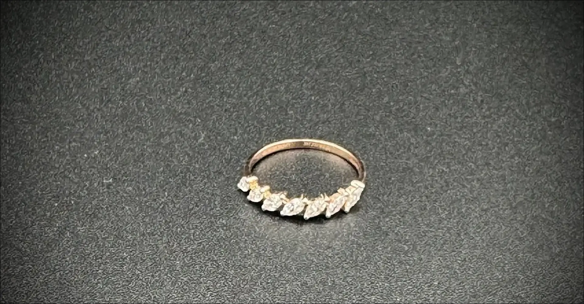 Elegant ring with seven marquise-cut stones on a textured surface.